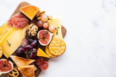 Peynir tabağı üzüm, reçeli, incir, kraker ve beyaz zemin üzerine fındık ile devam eder. Uzay kopyalayın. Üstten görünüm.