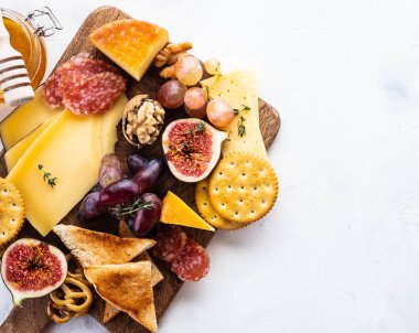 Peynir tabağı üzüm, reçeli, incir, kraker ve beyaz zemin üzerine fındık ile devam eder. Uzay kopyalayın. Üstten görünüm.