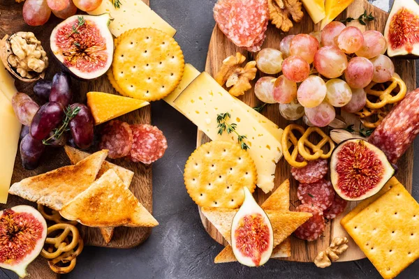 Cheese plate served with grapes, jam, figs, honey, crackers and nuts on a grey background. Copy space. Top view. — Stock Photo, Image