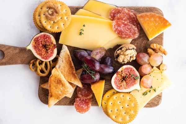 Prato de queijo servido com uvas, geléia, figos, bolachas e nozes em um fundo branco. Espaço para cópia. Vista superior . — Fotografia de Stock