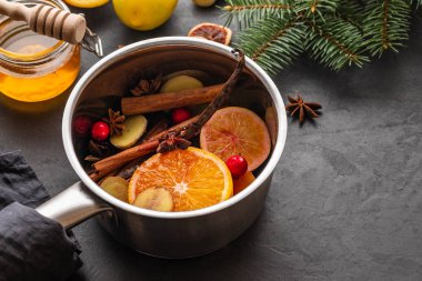 Narenciye, elma ve baharat alüminyum tencere ve köknar dalı arka plan üzerinde mulled şarap sıcak içecek.
