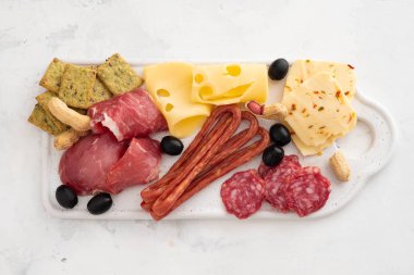 Geleneksel İspanyolca tapas - chorizo, salsichon, jamon serrano, lomo - erved zeytinli beyaz tahta üzerinde tedavi et tabağı.