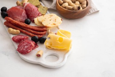 Geleneksel İspanyolca tapas - chorizo, salsichon, jamon serrano, lomo - erved zeytinli beyaz tahta üzerinde tedavi et tabağı.