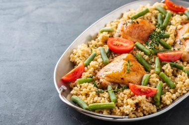 Bulgur, fasulye kuşkonmaz ve domates ile ızgara tavuk uyluk. Lezzetli yemegi.