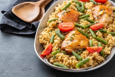 Bulgur, fasulye kuşkonmaz ve domates ile ızgara tavuk uyluk. Lezzetli yemegi.