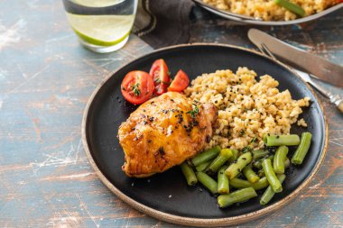 Bulgur, fasulye kuşkonmaz ve domates ile ızgara tavuk uyluk. Lezzetli yemek. Kopya alanı.