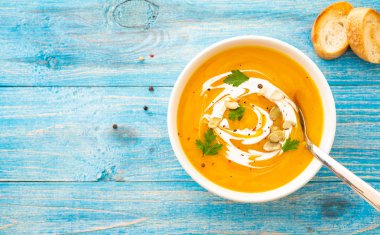 Maydanoz üzerinde mavi arka plan üstten görünüm kabak ve havuç çorbası.