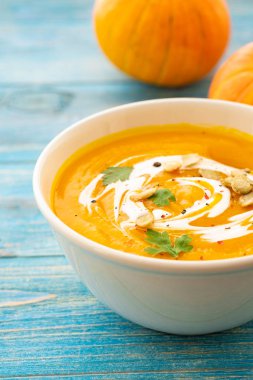 Maydanoz üzerinde mavi arka plan üstten görünüm kabak ve havuç çorbası.