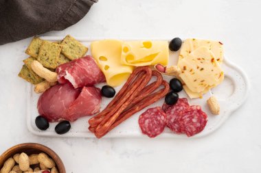 Geleneksel İspanyolca tapas - chorizo, salsichon, jamon serrano, lomo - erved zeytinli beyaz tahta üzerinde tedavi et tabağı.