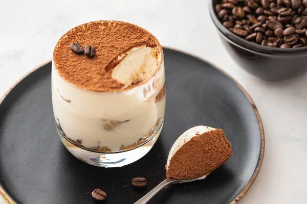 Delicioso tiramisu de sobremesa italiano, chocolate, cacau e grãos de café em um fundo preto. Espaço de cópia . — Fotografia de Stock