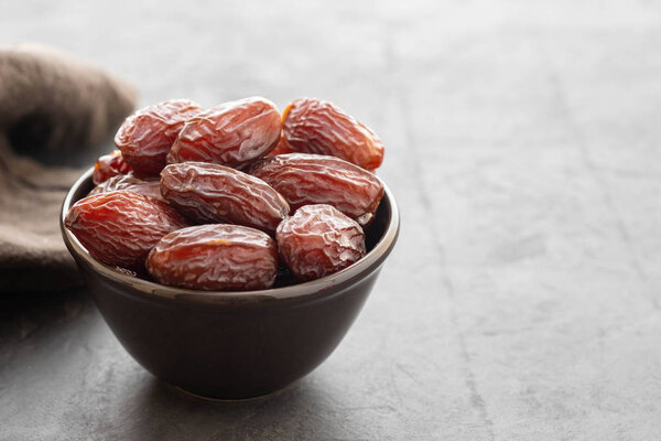 Fresh Medjool Dates in a bowl. Ramadan kareem. Black background. Top view. Copy space.