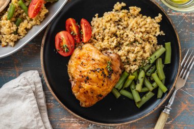 Bulgur, fasulye kuşkonmaz ve domates ile ızgara tavuk uyluk. Lezzetli yemek. Kopya alanı.