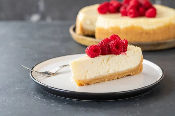 Slice of New York Cheesecake with raspberries on a dark background. — Stock Photo, Image