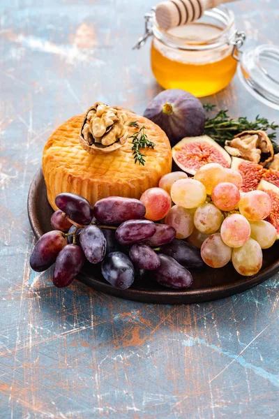 Prato de queijo servido com uvas, geléia, figos, biscoitos finos e nozes em um fundo . — Fotografia de Stock