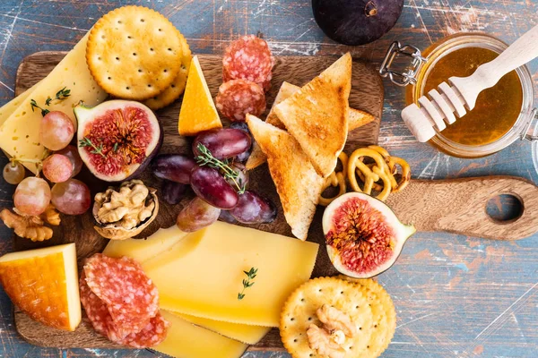 Prato de queijo servido com uvas, geléia, figos, biscoitos finos e nozes em um fundo . — Fotografia de Stock