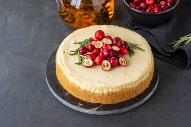 Klasik cheesecake kızılcık ve biberiye karanlık bir arka plan ile. Kış sürümü peynirli kek. Noel cheesecake.
