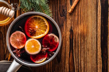 Narenciye, elma ve baharat alüminyum tencere ve köknar dalı arka plan üzerinde mulled şarap sıcak içecek.