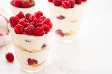 Ahududu tatlı, cheesecake, ahududulu tiramisu, önemsememek, mus bir bardak beyaz bir arka plan üzerinde.