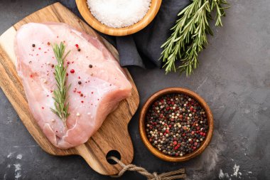 Baharat ve otlar ile siyah kesme tahtası üzerinde çiğ hindi fileto. Pişirme malzemeleri. Doğal sağlıklı gıda kavramı. Metin için yer ile üstten görünüm