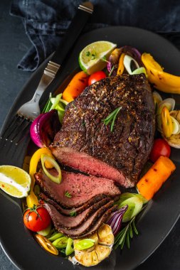 Biber sosu ve koyu ahşap arka plan üzerinde ızgara sebze sığır eti biftek kulübü. ROAS sığır eti. Kopya alanı.