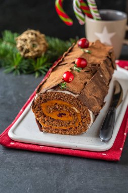 Buche de Noel. Geleneksel Noel tatlısı, Noel yule log kek Çikolata kremalı kızılcık. Noel ağacı dalları ile taş gri arka plan üzerinde.