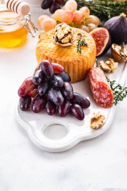 Üzüm, reçeli, incir, kraker ve bir arka plan üzerinde fındık ile peynir tabağı servis.