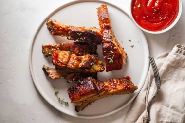 Barbekü domuz kaburga beyaz tabakta chili soslu. Domuz kaburga arduvaz arka plan üzerinde. Kopya alanı.