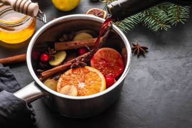 Narenciye, elma ve baharat alüminyum tencere ve köknar dalı arka plan üzerinde mulled şarap sıcak içecek.