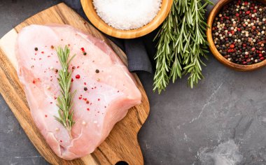 Baharat ve otlar ile siyah kesme tahtası üzerinde çiğ hindi fileto. Pişirme malzemeleri. Doğal sağlıklı gıda kavramı. Metin için yer ile üstten görünüm