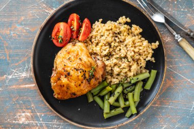 Bulgur, fasulye kuşkonmaz ve domates ile ızgara tavuk uyluk. Lezzetli yemek. Kopya alanı.