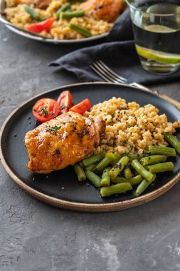 Bulgur, fasulye kuşkonmaz ve domates ile ızgara tavuk uyluk. Lezzetli yemek. Kopya alanı.