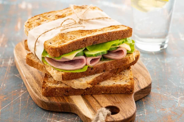 Close-up foto van een club sandwich. Sandwich met meet, ham, salami, salade, groenten, sla op een vers gesneden brood op houten achtergrond. Kopiëren van ruimte. — Stockfoto