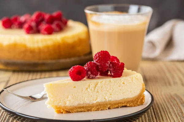 Piece of classic cheesecake with raspberries and coffee on a wooden background. Copy space. — Stock Photo, Image