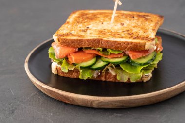 Tahıl ekmek ve karanlık mermer zemin üzerine somon sandviç. Kopya alanı.