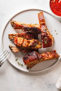 Barbekü domuz kaburga beyaz tabakta chili soslu. Domuz kaburga arduvaz arka plan üzerinde. Kopya alanı.