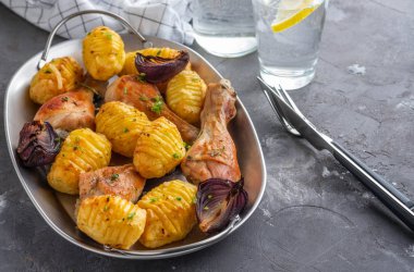 Patates kimyon ve siyah arka plan üzerine sarımsak ile kavrulmuş tavuk budu. Kopya alanı.