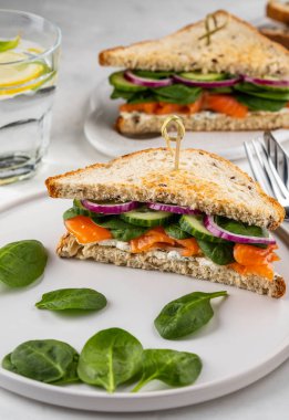 Krem peynir, somon ve ıspanak üzerinde beyaz bir artalanları sandviç.