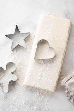 Ham puf böreği hamuru beyaz bir masada yatıyor. Pişirme için rakamlar metal kalıp kesme. Kopya alanı, üstten görünüm.