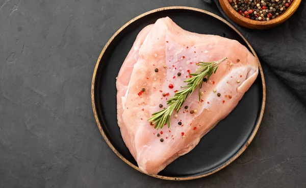 Baharat ve otlar ile siyah kesme tahtası üzerinde çiğ hindi fileto. Pişirme malzemeleri. Doğal sağlıklı gıda kavramı. Metin için yer ile üstten görünüm