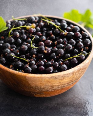 Ahşap bir kase siyah frenk üzümü. Yaz konsepti.