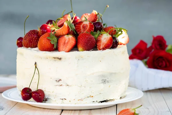 Pastel con bayas y crema en el fondo de la naturaleza . — Foto de Stock