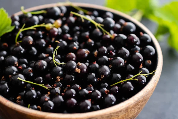Ahşap bir kase siyah frenk üzümü. Yaz konsepti.