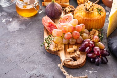 Üzüm, reçeli, incir, kraker ve bir arka plan üzerinde fındık ile peynir tabağı servis.