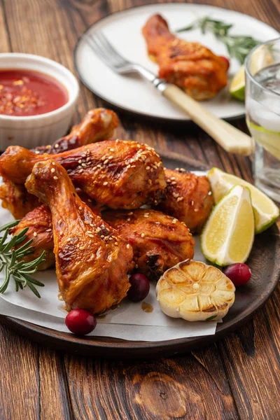 Tasty appetizing baked chicken legs served with spices, rosemary and cranberries on wooden background table. Christmas dish. Copy space.