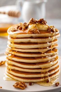 Lezzetli kahvaltı. Gri arka planda ezilmiş ceviz, bal veya akçaağaç şurubu ile ev yapımı krep.