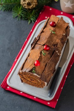Buche de Noel. Geleneksel Noel tatlısı, Noel yule log kek Çikolata kremalı kızılcık. Noel ağacı dalları ile taş gri arka plan üzerinde.