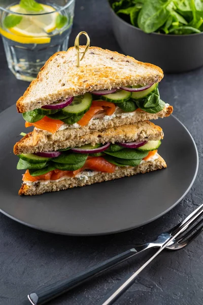 Sandwiches con queso crema, salmón y espinacas sobre un fondo oscuro . —  Fotos de Stock