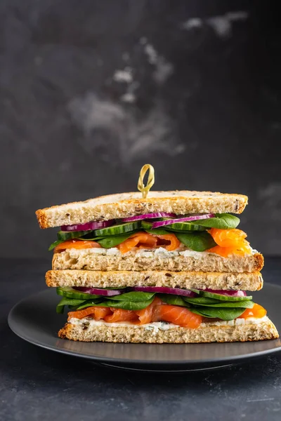 Sandwiches con queso crema, salmón y espinacas sobre un fondo oscuro . —  Fotos de Stock