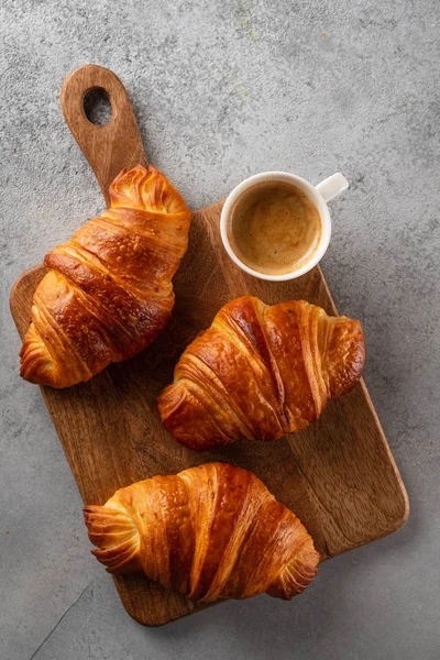 Petit déjeuner avec croissants, planche à découper et café noir. Couché plat, vue du dessus . — Photo