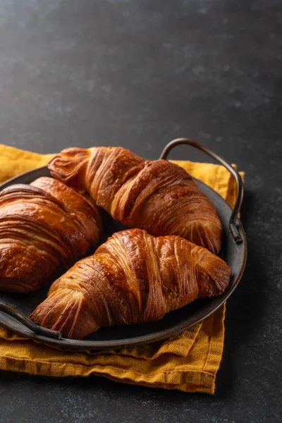 Croissants recém-assados na bandeja vintage. montão de croissants recém-assados no fundo escuro. Pastelaria francesa — Fotografia de Stock